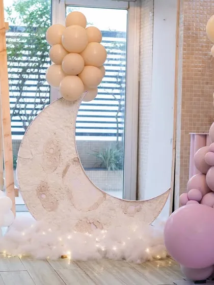 A large, light-up moon prop resting on a bed of fluffy clouds, creating a magical photo spot at the "We Can Bearly Wait" baby shower.