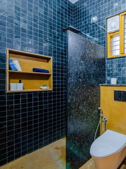 The dark tiles and granite partition create a sophisticated and moody atmosphere in this bathroom.