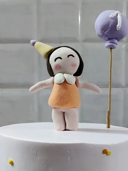 A handmade fondant topper of a little girl holding a balloon. I can create custom toppers to personalize your cake.
