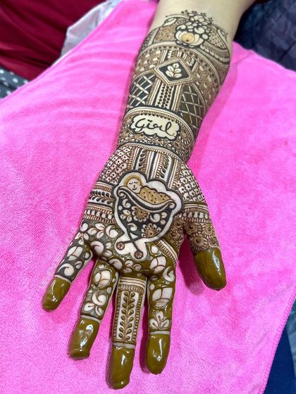 A close-up of a baby shower design featuring a baby in a cradle on the palm and the word "Girl" on the arm.