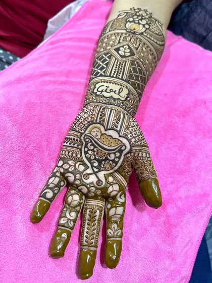 A close-up of a baby shower design featuring a baby in a cradle on the palm and the word "Girl" on the arm.