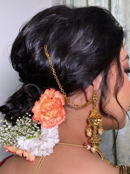 A close-up of this elegant bridal bun, decorated with fresh carnations and baby's breath. Floral buns are a beautiful way to add a touch of freshness and tradition to your wedding look.