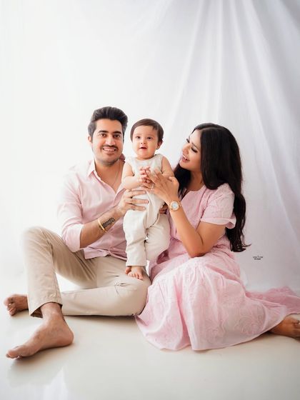 A happy family of three, with the little one standing tall with the help of his parents.