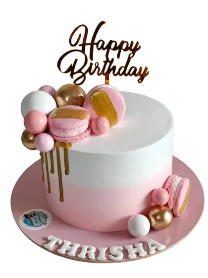 A modern birthday cake with a pink and white ombre effect, gold drip, and macarons. This is a chic and stylish design for any celebration.