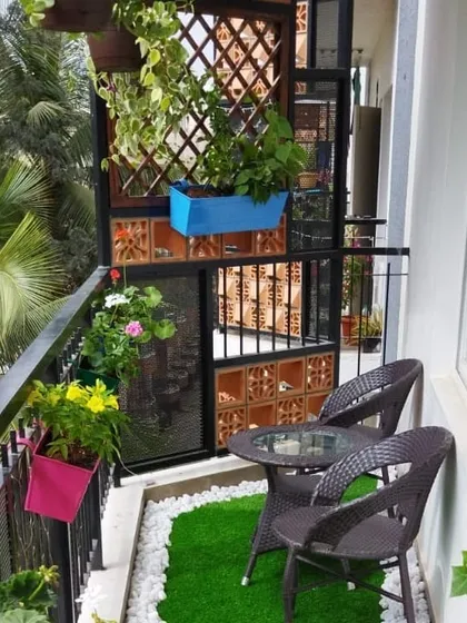 This balcony setup combines natural elements and comfortable seating. We used a mix of hanging plants, railing planters, and a wooden trellis to create a private, green retreat.