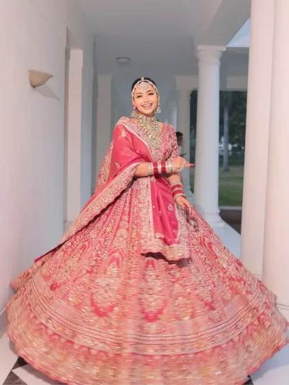 A full-length shot of the bride in her magnificent red lehenga. The makeup is designed to be fresh-faced and flawless, making her glow from within.