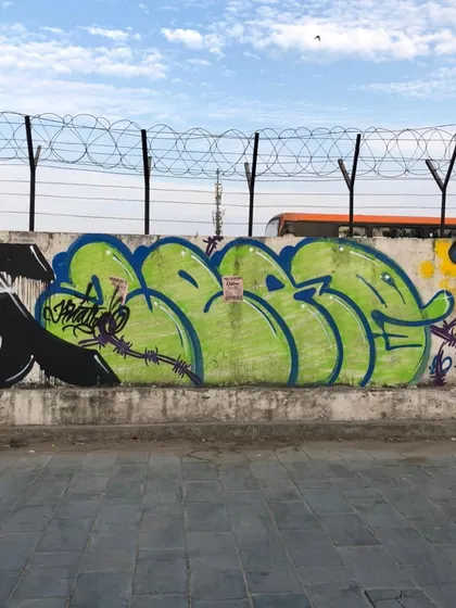 A green bubble-style throw-up on a concrete wall, showing how this style stands out in an urban environment.
