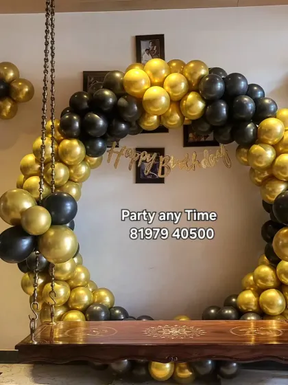 Another view of the black and gold balloon arch on the swing, showing how it can transform a living room space.