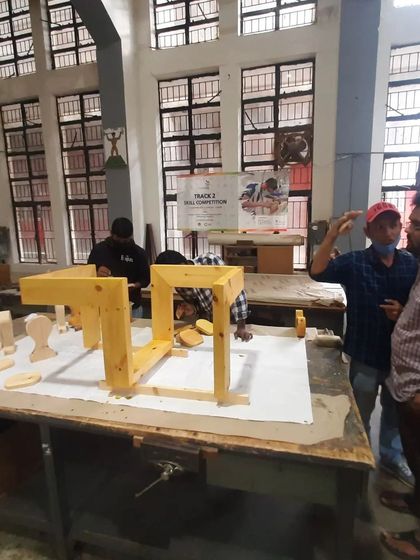 Students discuss the assembly of a geometric table base, problem-solving the best sequence for putting the interlocking pieces together.