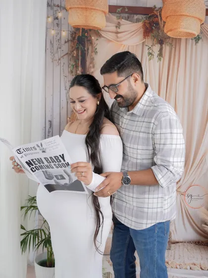 Let's have some fun with your announcement! This couple shared a laugh over a custom "New Baby Coming Soon" newspaper in our cozy boho-themed studio setup. These playful moments create such warm, authentic memories.
