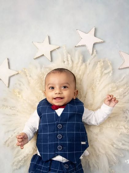 A little star on cloud nine. This infant portrait uses a soft, fluffy rug and wooden stars to create a dreamy, celestial-themed setup for a baby boy.