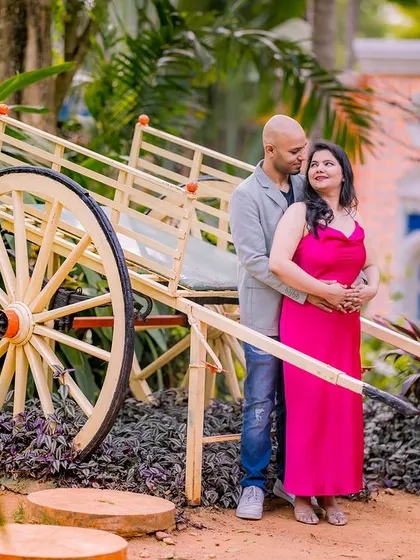 A couple poses with a rustic bullock cart, a unique and charming prop in our garden.