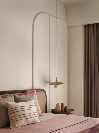 The curved 3D cut-outs on the wall serve as minimalist art, complemented by a simple pendant light. This design choice adds architectural interest without cluttering the serene space.