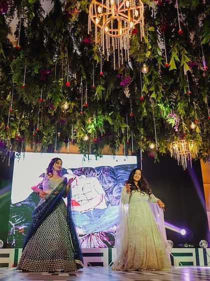 A graceful moment from a sisters' duet performance. The LED screen in the background shows a childhood photo, adding a personal and emotional touch.