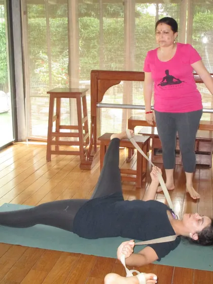 A student receives a one on one adjustment in Supta Padangusthasana. This close attention ensures she understands the correct action of the leg and hip.