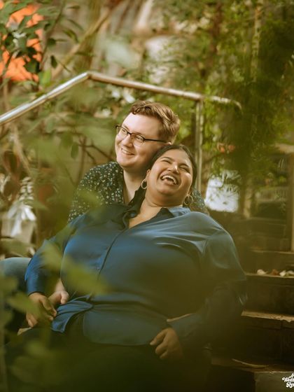 A joyful, candid moment of laughter shared between a couple on a staircase, showing their easy and natural chemistry.