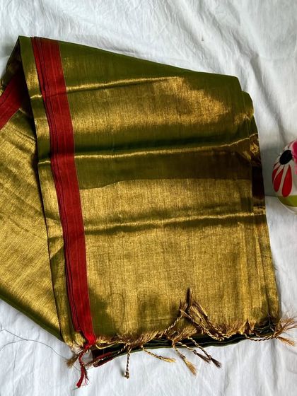 A mehendi green tissue cotton saree with a red border. The possibilities for styling this are endless, from a simple gold blouse to a printed one.
