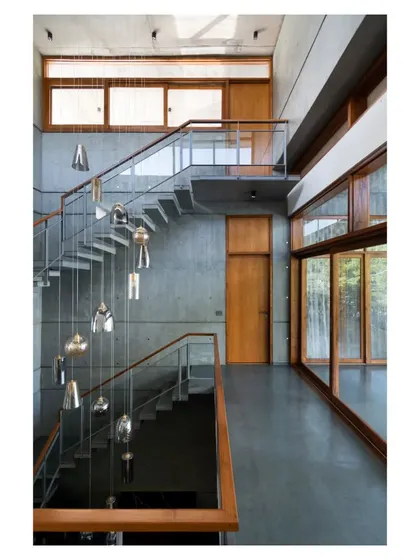A cascade of pendant lights hangs through the triple-height stairwell, accentuating the vertical volume and drawing the eye upwards.
