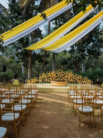 The seating area for an outdoor Haldi ceremony, with yellow and white drapes creating a bright and cheerful canopy.
