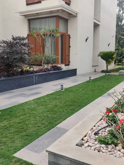 A long, linear garden path flanked by manicured lawns and flower beds. This design uses clean lines and formal planting to create a sense of order and elegance, leading the eye through the space.