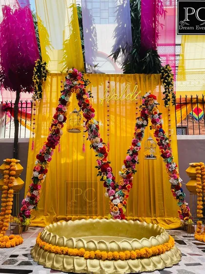 Another angle of the 'M' shaped Haldi arch, showing the colorful drapes in the background that add to the festive look.