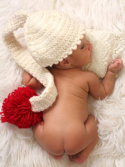 A playful and adorable shot from behind, showing the baby's back while wearing a cute pom-pom hat. It's a unique angle that captures their tiny, perfect form.