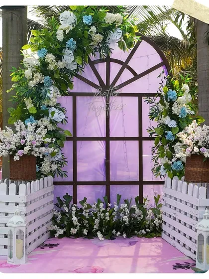 A charming photo corner with a rustic window frame, white picket fences, and blue and white floral arrangements. The "Better Together" neon sign adds a modern, romantic touch.
