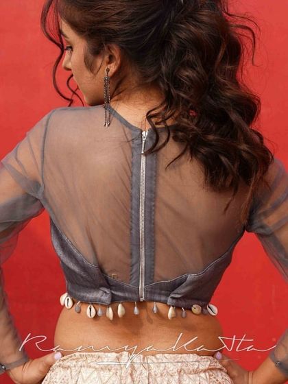 A unique detail on the back of the blouse, featuring a zip closure and a hemline adorned with cowrie shells for a bohemian touch.
