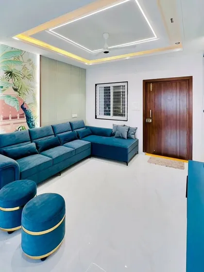 A vibrant living room with a large L-shaped teal sofa. The design includes a modern TV unit and a feature wall with a painted mural, creating a fresh and contemporary space.