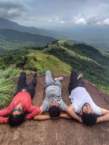 Taking a well-deserved rest at the summit of the Kurinjal trek, with panoramic views of the shola grasslands.