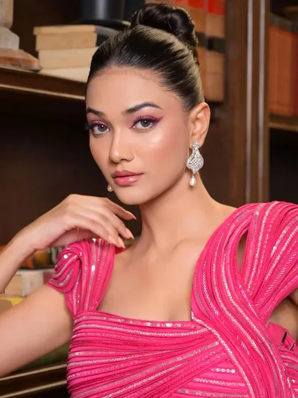 A close-up portrait where the sleekness of the top-knot hairstyle accentuates the model's sharp features and the dramatic eye makeup.