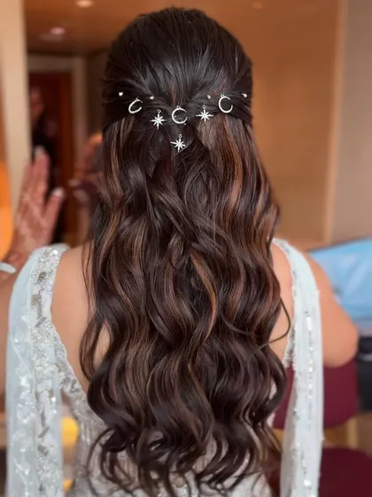 A detailed shot of the half updo with moon and star charms, showing how they catch the light. It's a whimsical and modern choice for a fun wedding event.