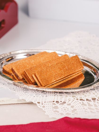 A close-up of our crisp, buttery caramel cigar fingers, elegantly served on a silver platter. A delightful addition to any festive hamper.