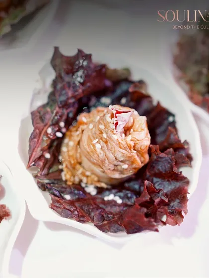 An artfully constructed bite-sized appetizer, featuring a swirl of savory filling nestled in a crisp, purple lettuce cup. This is an example of our dedication to exquisite, handcrafted canapés.