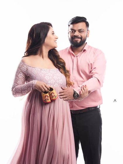 A sweet announcement photo, with the couple holding up tiny shoes. The matching pink tones in their outfits create a cohesive and lovely portrait.