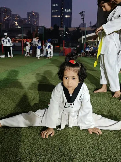 With a little help and encouragement, students can push their limits. Here, another student helps Anika with her splits, showcasing the supportive community we build in our classes.