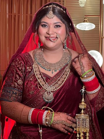 Glowing like a queen in her traditional red attire. The makeup features a radiant base and defined eyes, perfect for a classic Indian wedding ceremony.