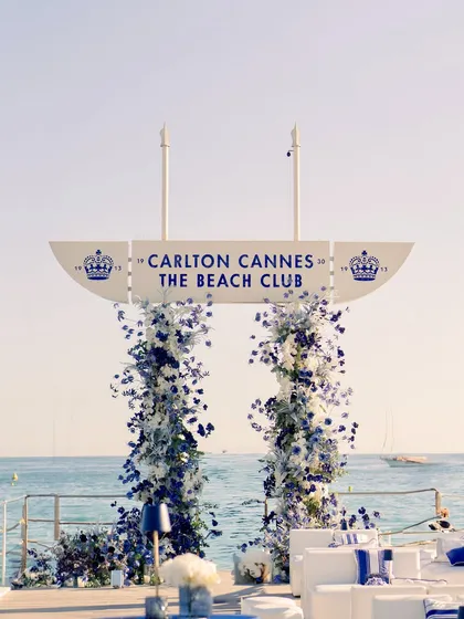 The floral entrance arch stands proudly against the iconic Carlton Cannes sign, creating a picture-perfect welcome for the guests.