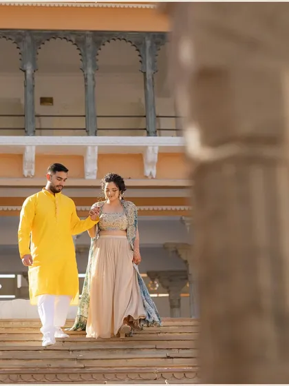 The couple walks hand-in-hand down the steps of a palace, framed by an archway. This shot captures a natural, in-between moment with a beautiful architectural element.