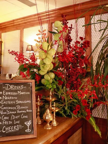 A bar decorated for a Diwali launch event, with a large floral arrangement and traditional brass diyas.
