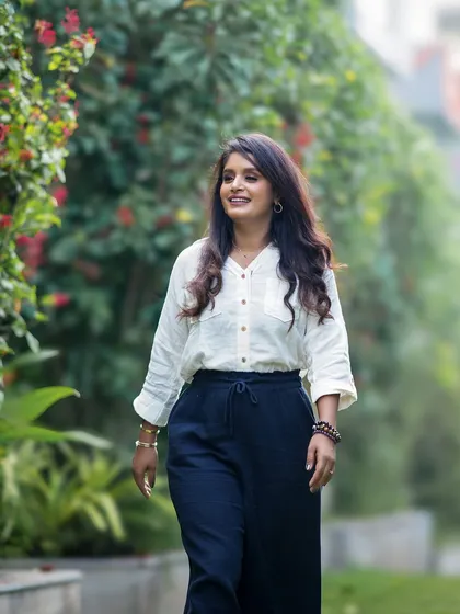 A confident portrait of a woman walking through a green corridor, smiling and looking at ease.