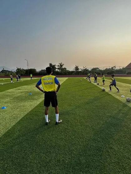 A coach observes a training session as the sun sets over the academy pitch. This scenic shot captures the dedication of our coaches and the beautiful environment our players train in.