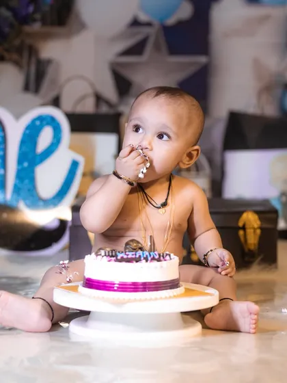 A moment of quiet contemplation before diving back into the cake. This shot captures the adorable, frosting-covered fingers of a one-year-old.