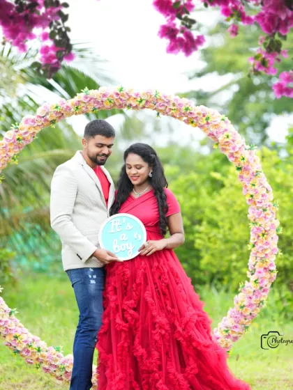 A sweet gender reveal photo with a sign announcing "It's a boy!". The couple is framed by a circular floral prop.
