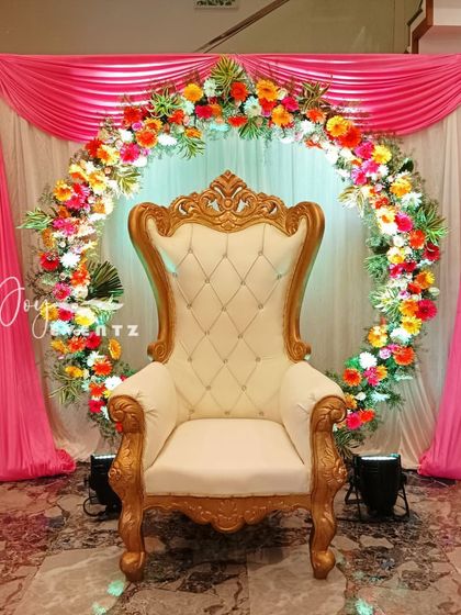 A beautiful floral ring backdrop perfect for a half saree function at home. We use a mix of colorful flowers to create the ring, complemented by elegant pink drapes and a classic throne chair.