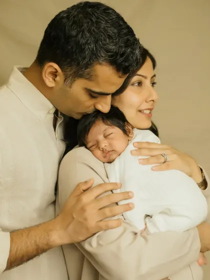 A father's gentle kiss on his newborn's head while the mother holds their baby close. A truly timeless and emotional family portrait.
