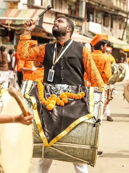The same moment of musical bliss, with the dhol player raising his stick, surrounded by the energy of the band.