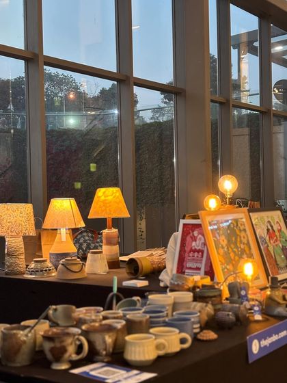 Our stall setup, with handmade lamps, framed art, and a table full of ceramic treasures.