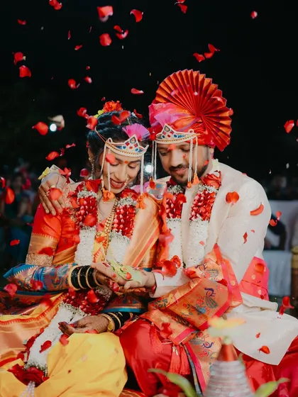 A classic Maharashtrian wedding moment, showered in flower petals. The vibrant colors of the bride's navari saree and the groom's pheta come alive in this shot from a beautiful Raigad wedding.