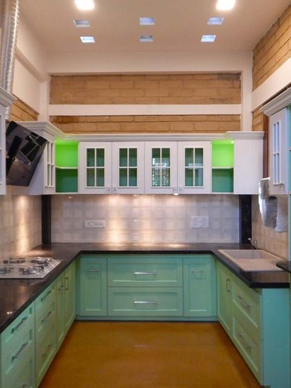 A classic kitchen design with mint green and white cabinets, glass-fronted upper shutters, and a black granite countertop, creating a fresh and timeless look.